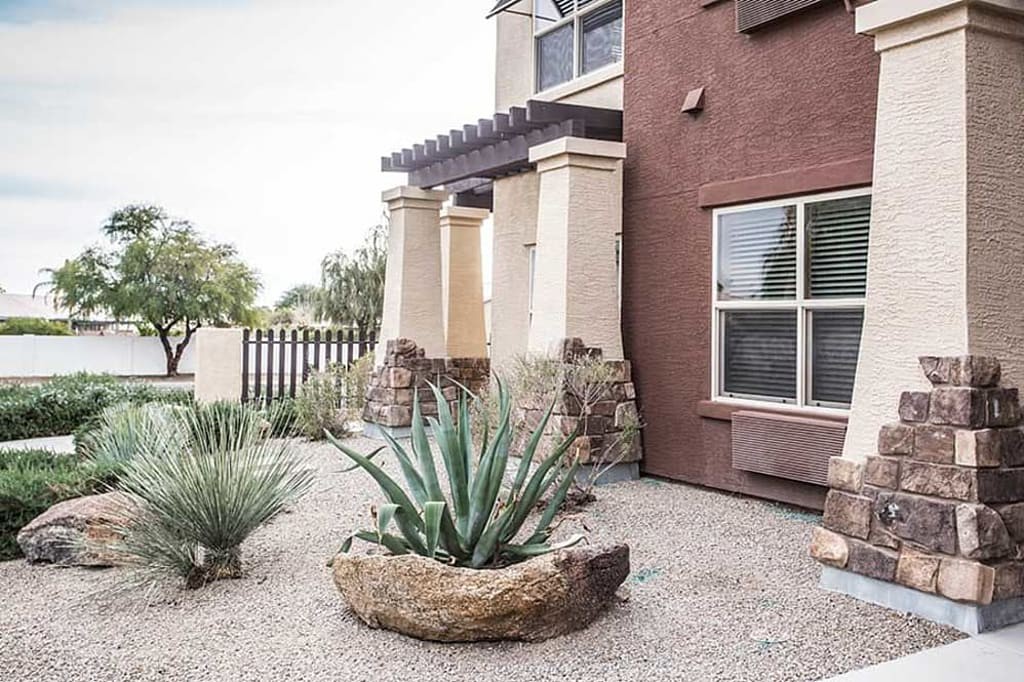 A modern home's front yard featuring a desert landscape with succulents and stone accents.