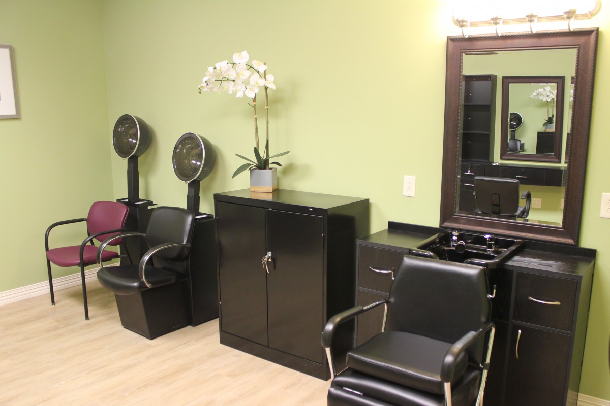 A modern salon interior with hair drying stations and seating.