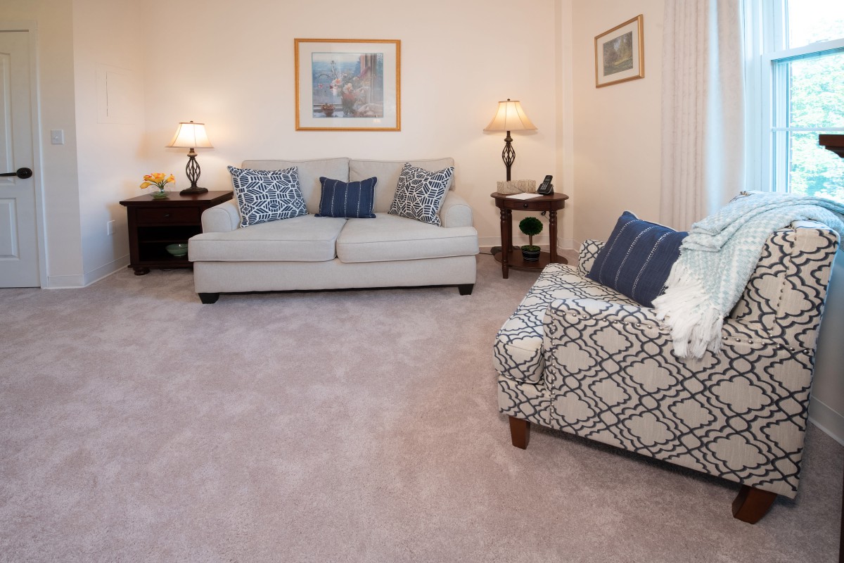 A cozy living room with a sofa and armchair, featuring patterned cushions and soft lighting.