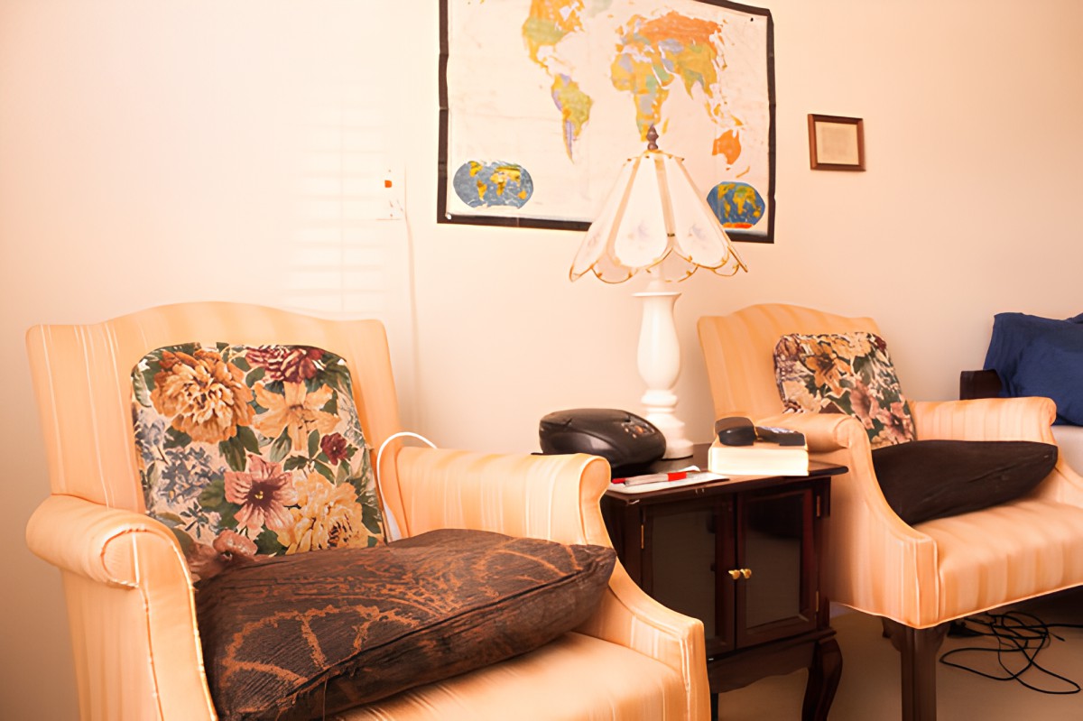 A cozy living room setting with two armchairs, a side table, and a world map on the wall.