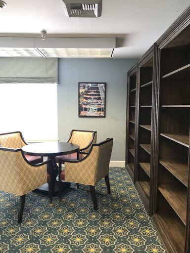 A quiet reading area with a table, chairs, and empty shelves in a library.