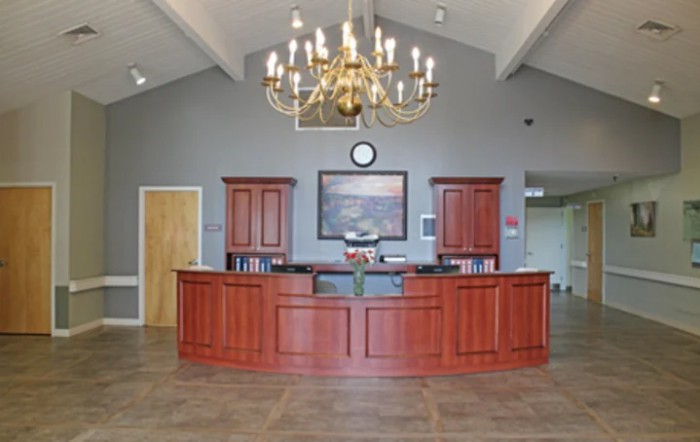 A spacious reception area featuring a wooden desk and a large chandelier.