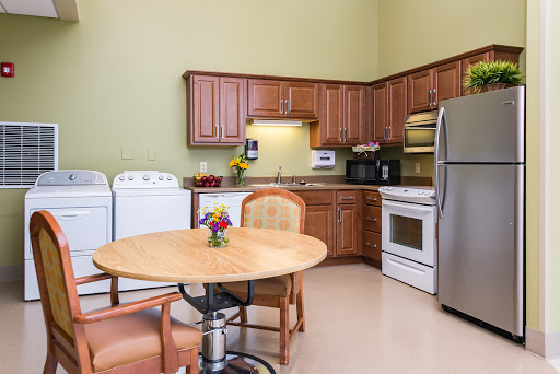 A cozy kitchen showing wooden cabinets, a dining table, and modern appliances.