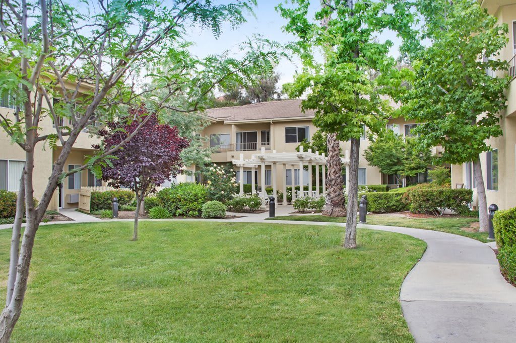A residential building surrounded by well-maintained landscaping and a winding pathway.
