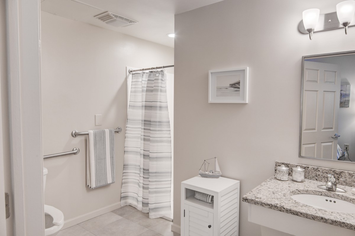 A modern and minimalist bathroom with a striped shower curtain and neatly folded towels.
