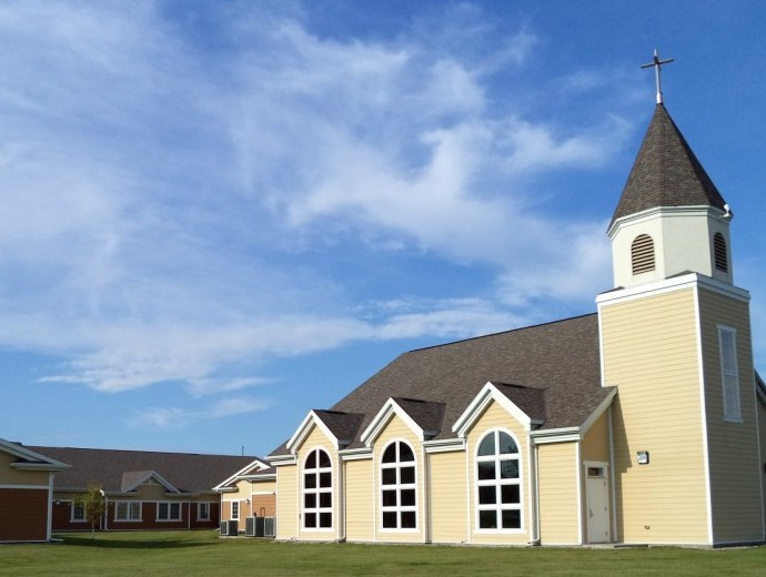 A picturesque church with a steeple under a blue sky with clouds.