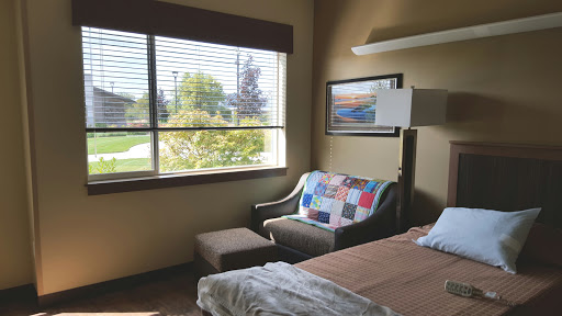 A cozy room featuring a bed, colorful couch, and large window allowing natural light to fill the space.