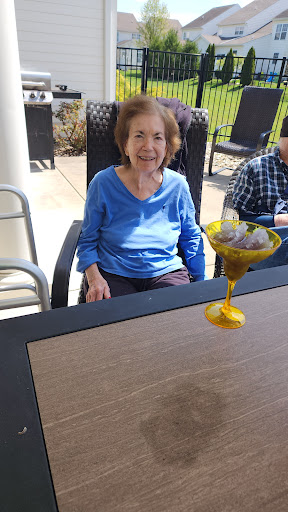 An elderly woman enjoying a drink outdoors on a sunny day.
