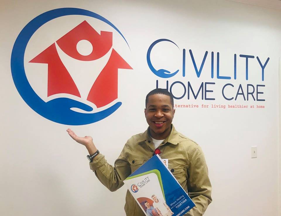 A person stands in front of a wall with the 'Civilta Home Care' logo, holding a brochure.