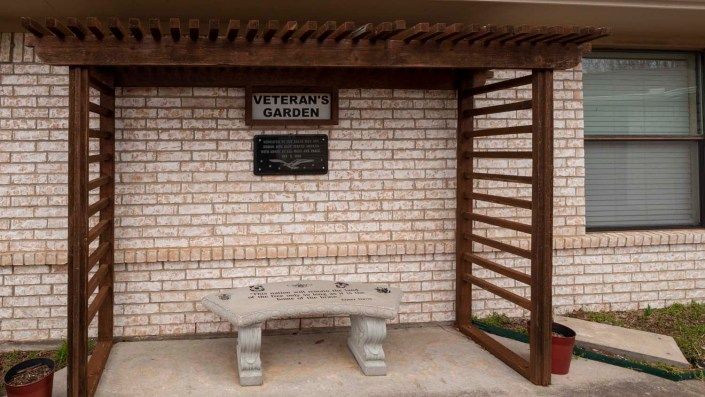 A Veterans Memorial area with a bench and commemorative plaques on a brick wall.