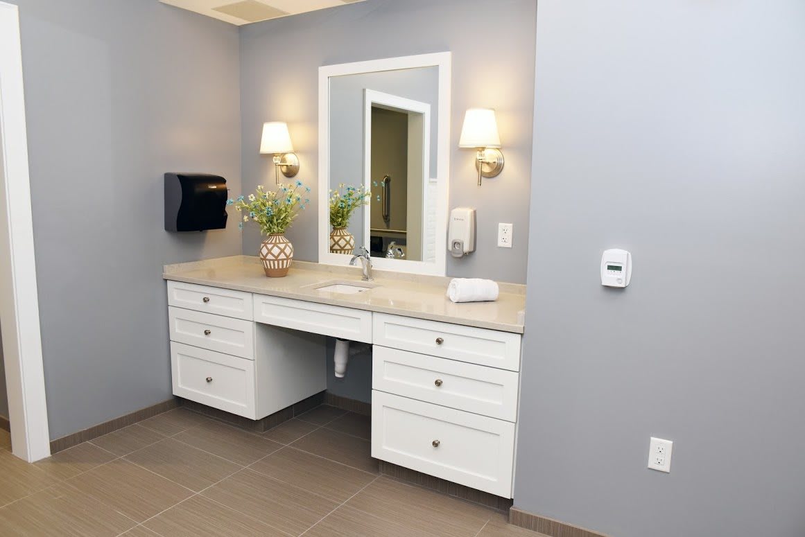 A modern bathroom vanity area with a large mirror and elegant lighting.