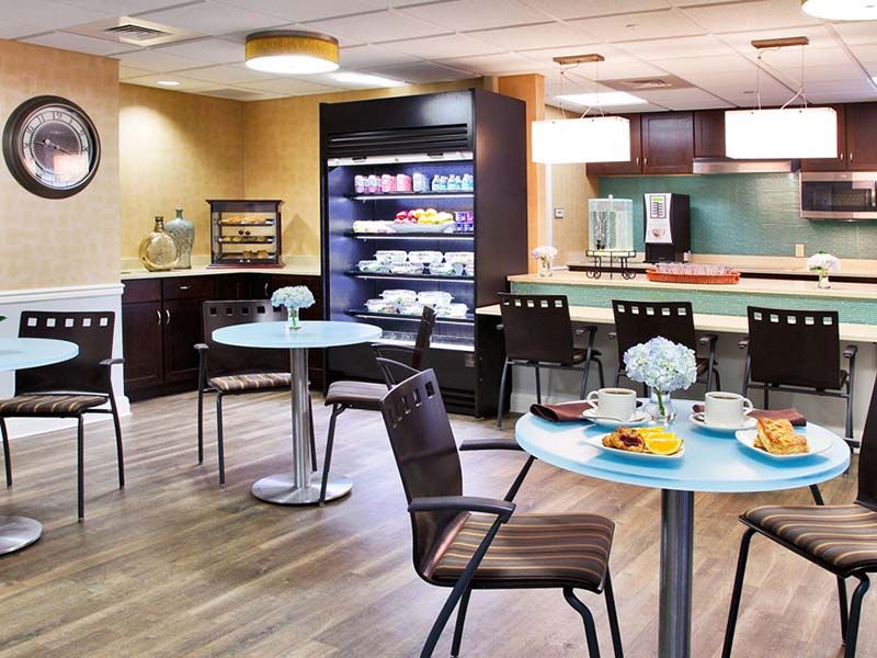 A cozy cafe interior with tables set for breakfast and a well-stocked beverage station.