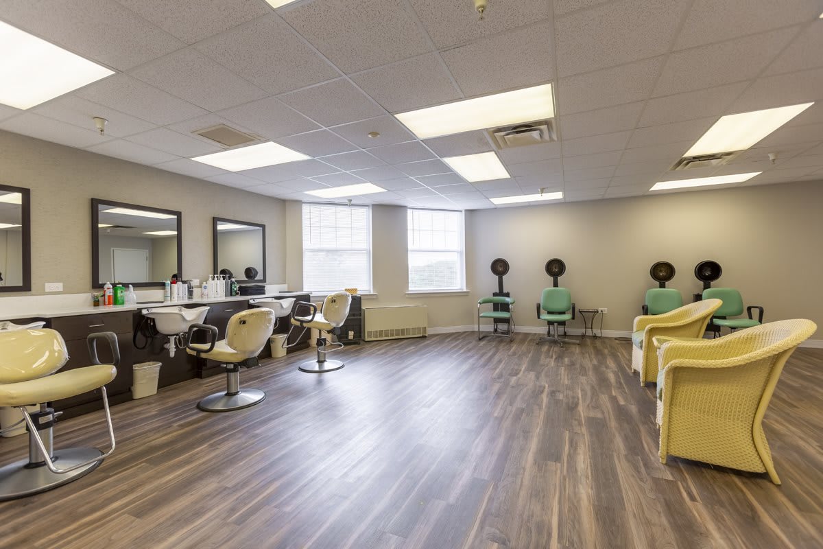 A spacious salon interior with chairs, mirrors, and hair dryers.