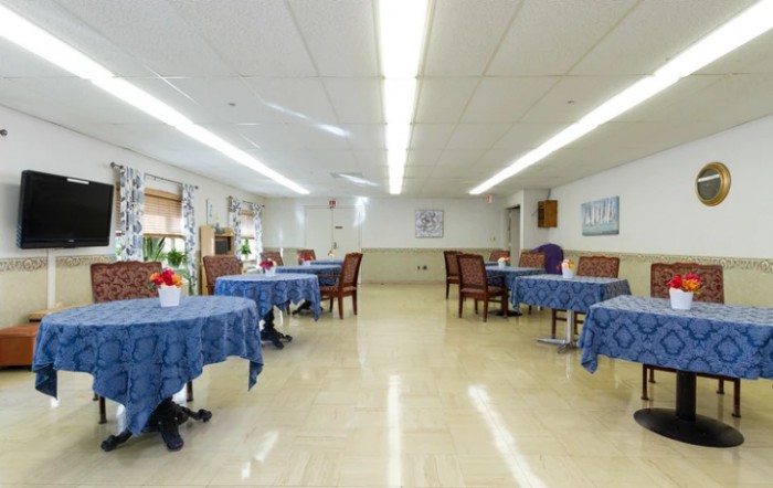 A spacious dining area with blue tablecloth-covered tables and chairs.