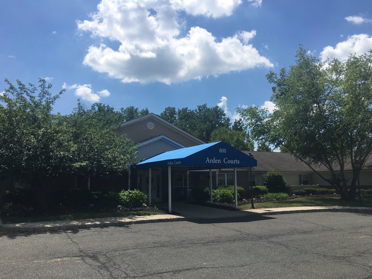 A building with a blue canopy on a sunny day with clouds in the sky.
