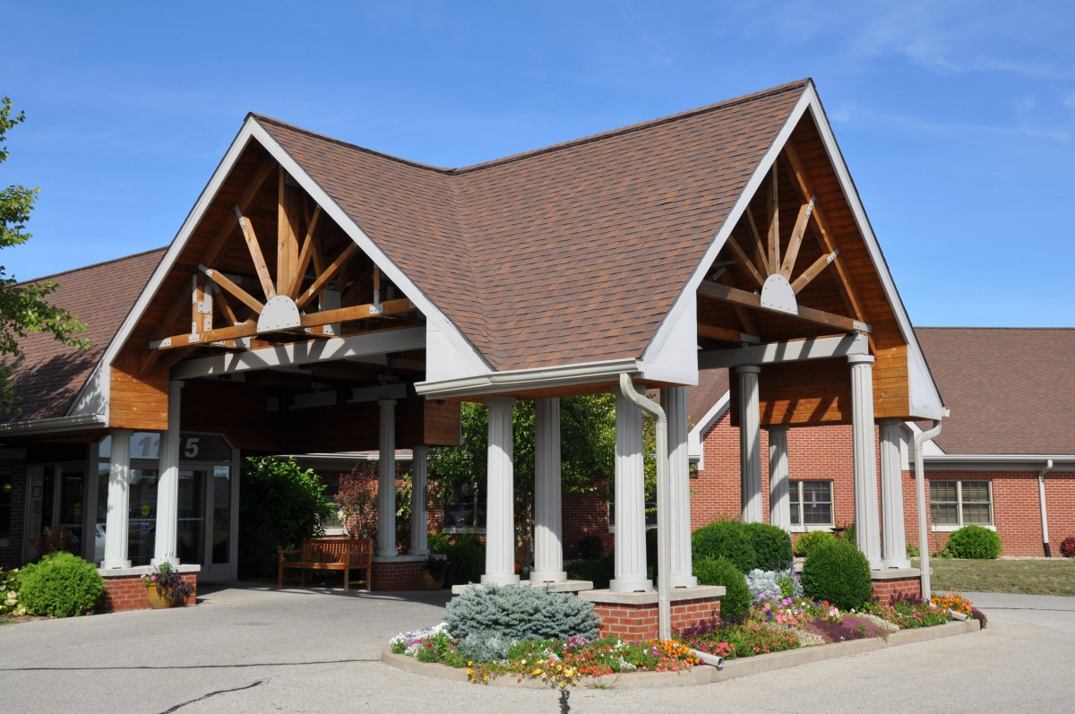 A building entrance with a triangular roof and supporting columns.