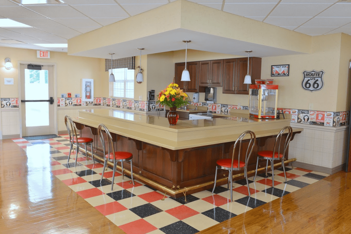 A retro-style kitchen with a checkerboard floor and island counter surrounded by bar stools.