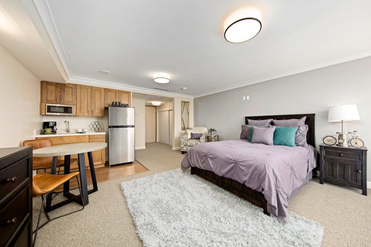 A modern studio apartment featuring a cozy bedroom and compact kitchen area.