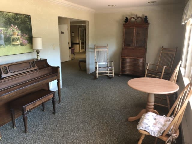 A cozy living room featuring vintage furniture, including a piano and rocking chairs.