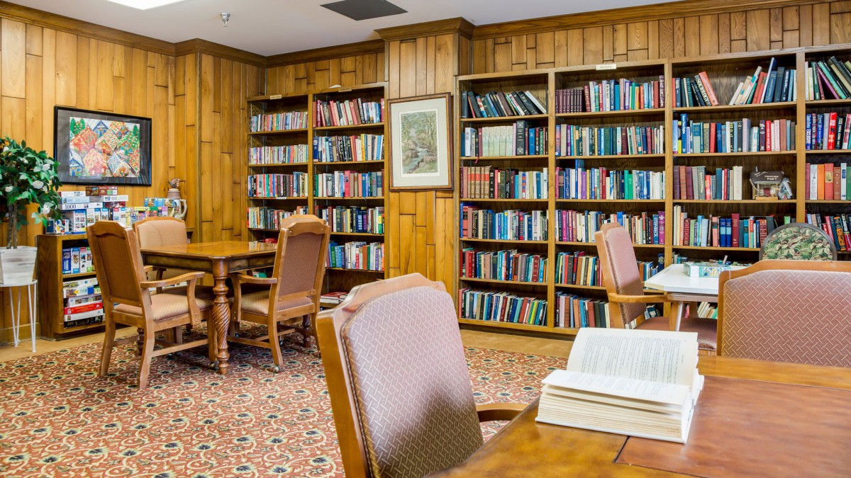 A cozy library reading room with shelves full of books and comfortable seating.