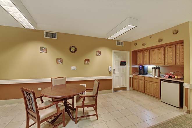 A cozy kitchen area with a round table and chairs, surrounded by cabinets and wall decor.