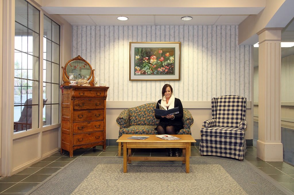 A woman reads on a sofa in a cozy living room with stylish furniture and artwork on the wall.