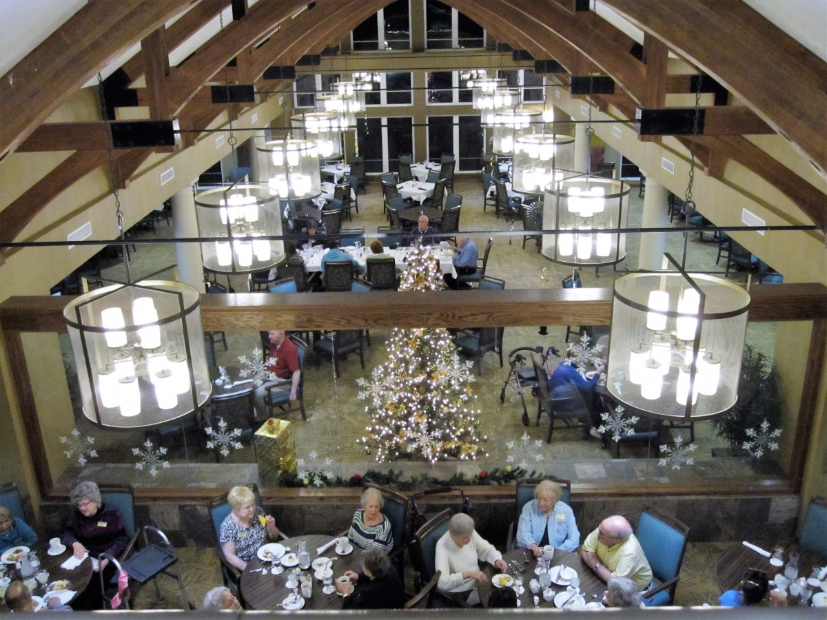 A spacious dining hall adorned with chandeliers and festive decorations, where people are enjoying a meal.