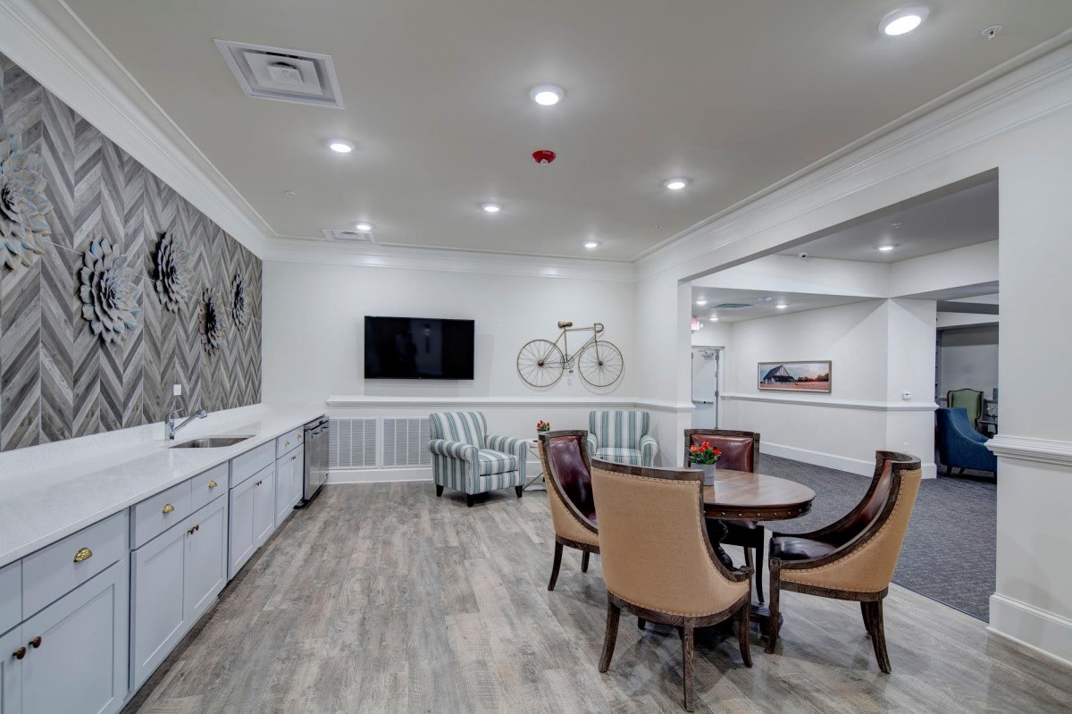 A modern dining area with stylish seating and a wall-mounted television, featuring a decorative bicycle and wood flooring.