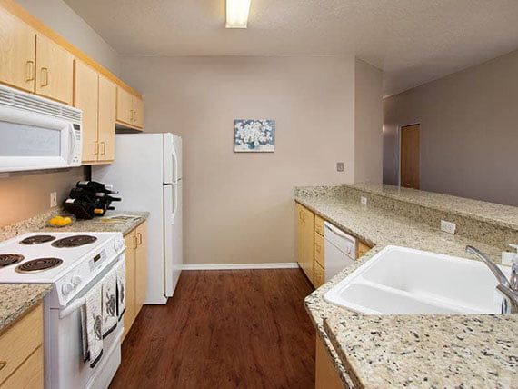 A modern kitchen featuring wood flooring, granite countertops, and various appliances.