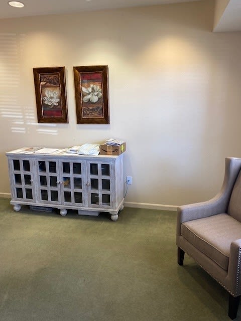 A cozy waiting room with a cabinet and artwork on the wall.