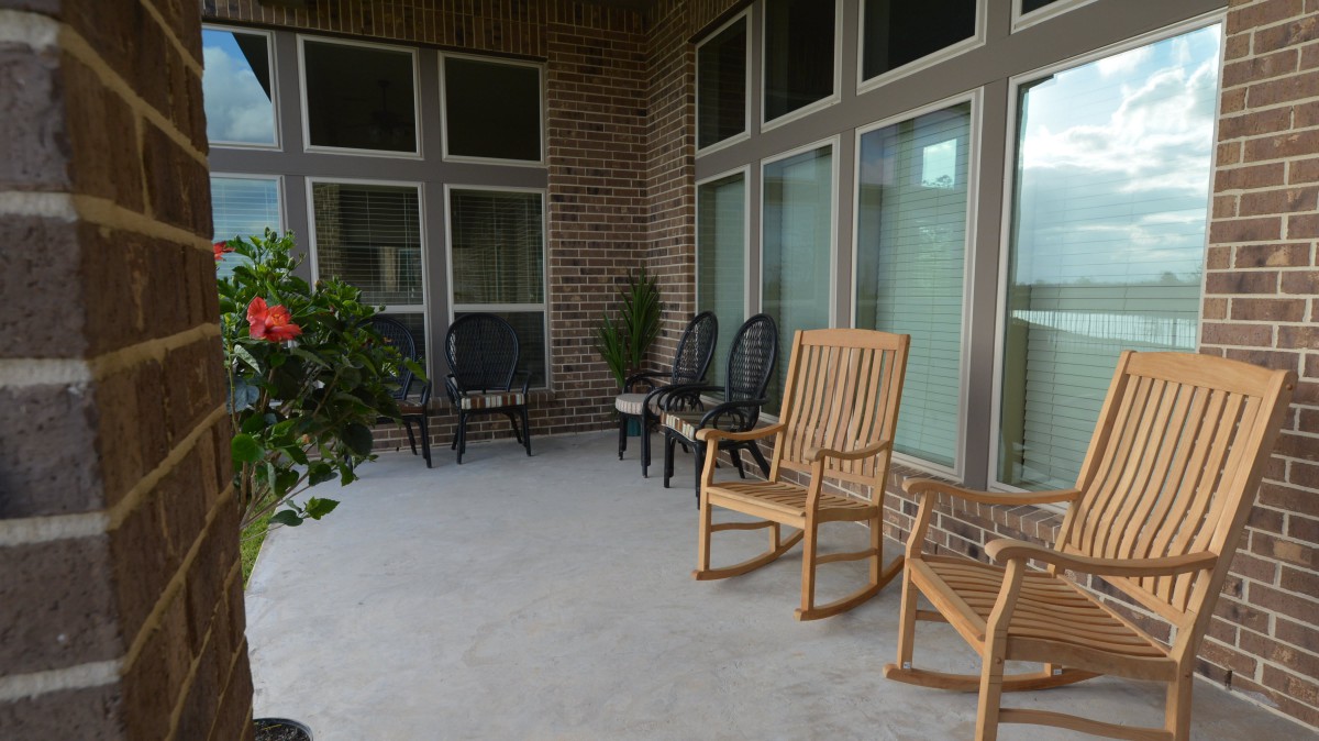 A cozy porch with rocking chairs and additional seating against a brick wall.