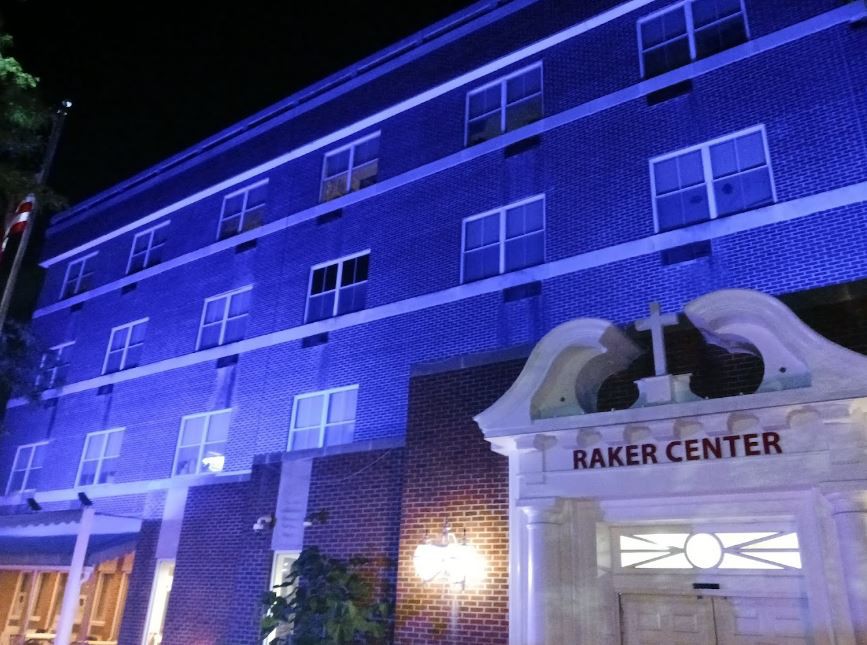 A building illuminated with blue lights at night, featuring a sign that reads 'Baker Center'.