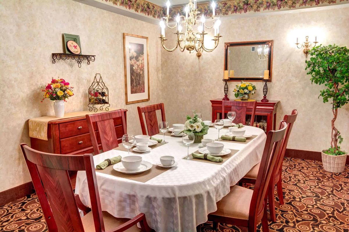 An elegant dining room with a formally set table and a chandelier overhead.