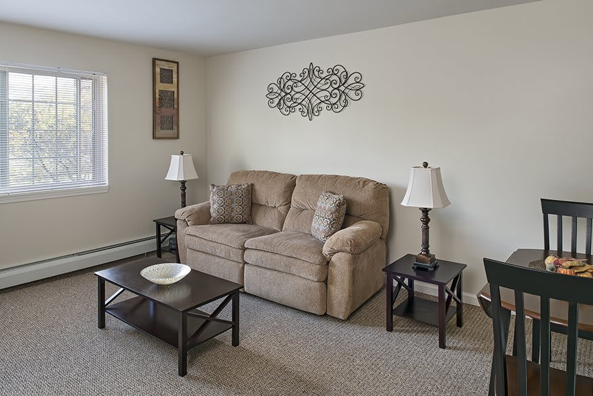 A cozy living room with a comfortable sofa, two lamps, and stylish coffee tables.