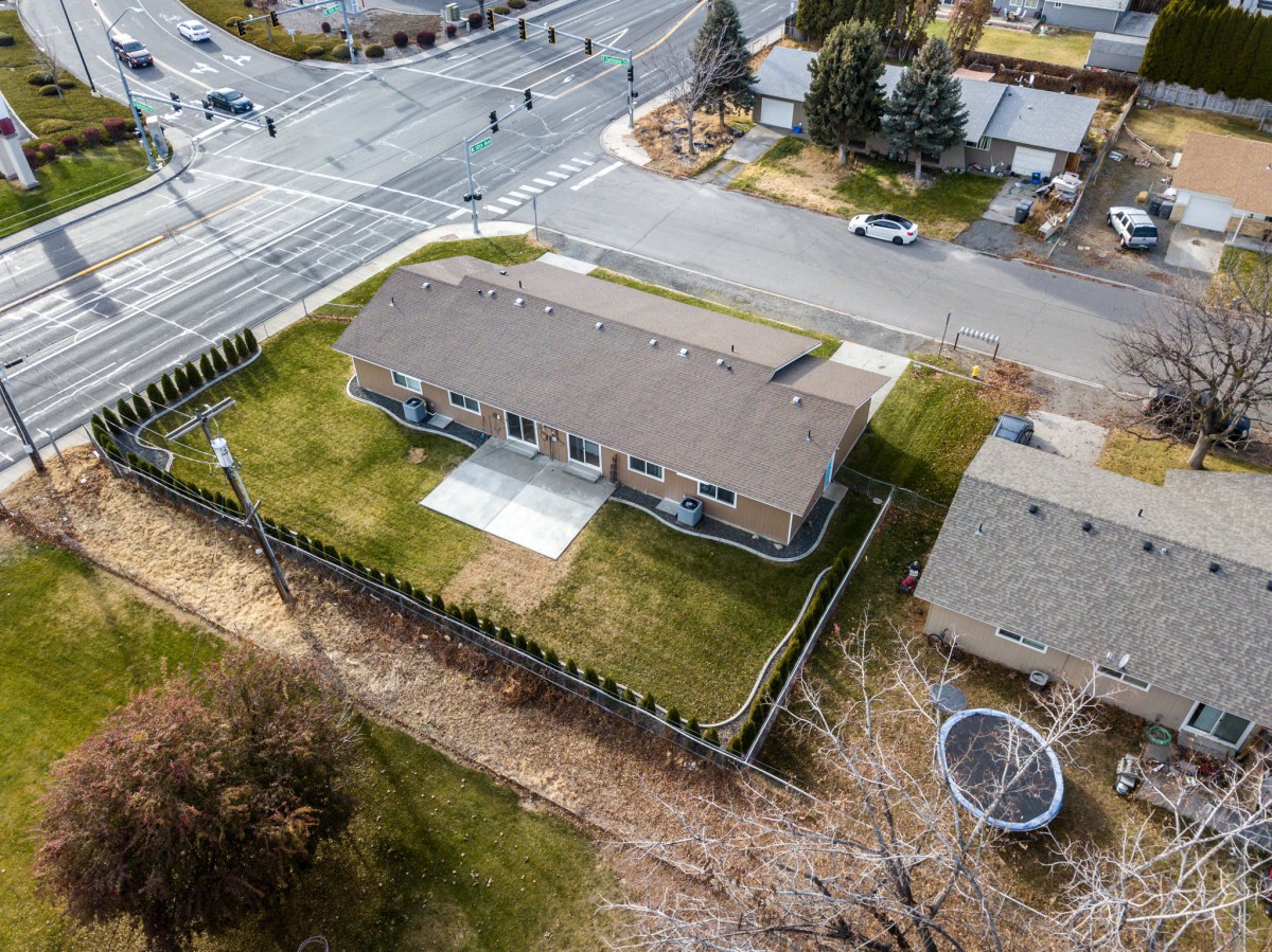 Aerial view of a house with a fenced yard located at the corner of an intersection.