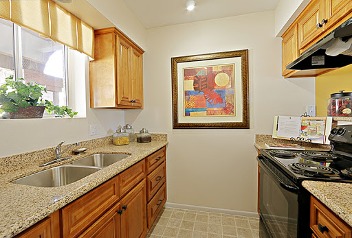 A cozy kitchen featuring wooden cabinets, modern appliances, and colorful artwork.