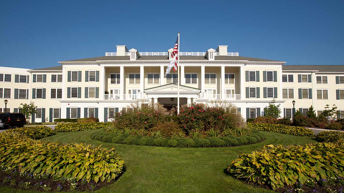 A historic building with a well-maintained garden and an American flag flying prominently.