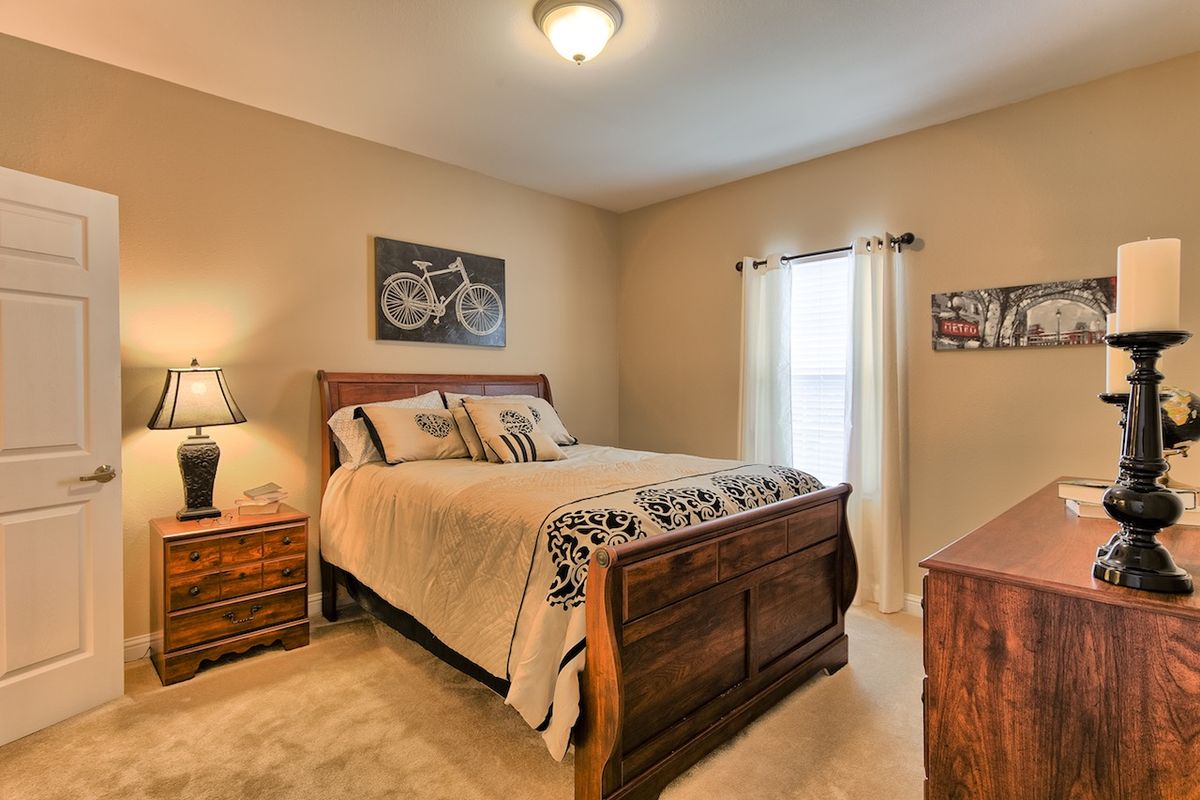 A cozy bedroom featuring a wooden bed frame with a quilted comforter, nightstands with lamps, and bicycle-themed artwork on the walls.