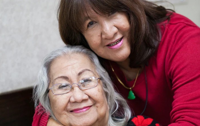Two smiling women embracing, showcasing warmth and togetherness.