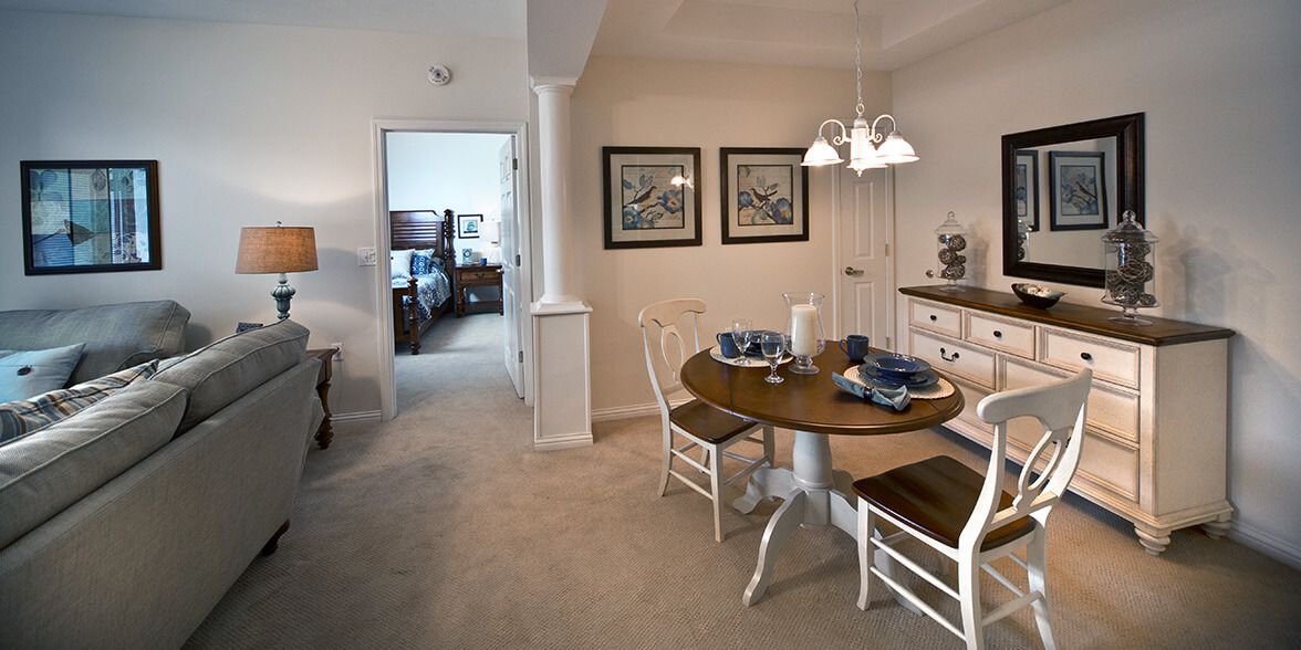 A cozy dining area with a wooden table and chairs, decorated with artwork and warm lighting.