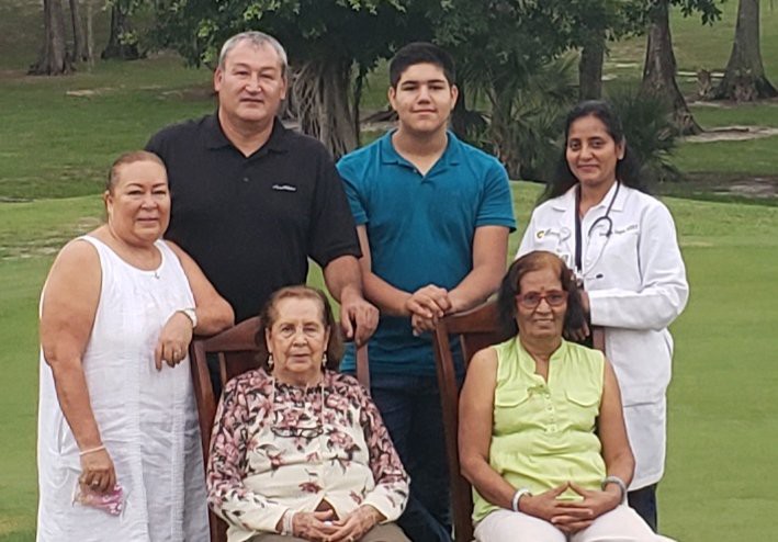 A multi-generational family gathered outdoors for a group photo, with everyone smiling.