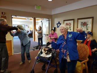 A group of elderly individuals having fun and dancing in a community setting.
