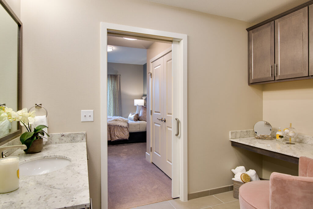 A modern bathroom with a view of an adjacent bedroom through an open doorway.
