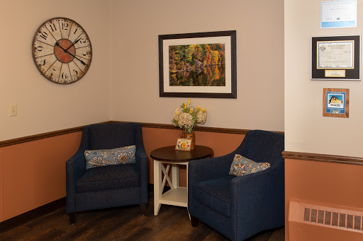 A cozy seating area featuring two blue chairs, a small table, and decorative wall art.