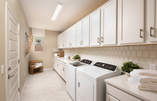 A bright and organized laundry room featuring white cabinetry and modern appliances.