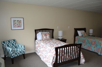 A cozy bedroom featuring two twin beds with patterned bedding and a bedside table with a lamp.