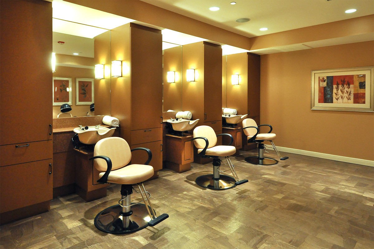 A modern hair salon with stylish chairs and mirrors, warmly lit for a relaxing atmosphere.