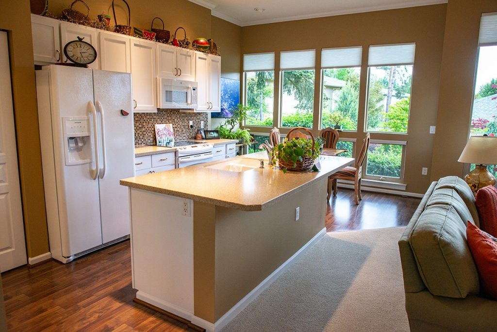 A bright and spacious kitchen with an island, large windows, and wooden flooring.