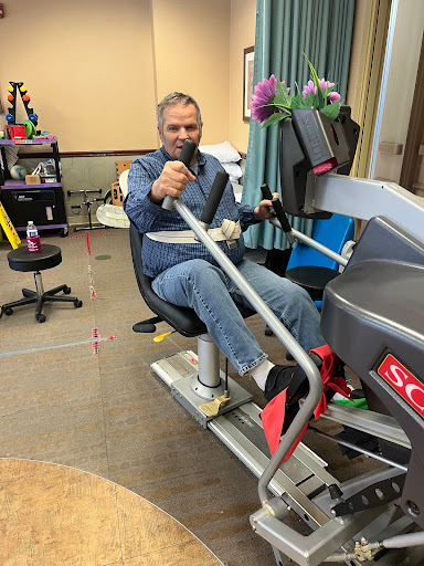 A man engaging in a workout session on a rowing machine, emphasizing rehabilitation and fitness.