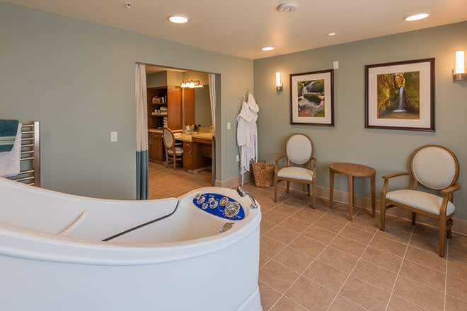 A luxurious spa-like bathroom featuring a modern bathtub, cozy seating area, and calming decor.